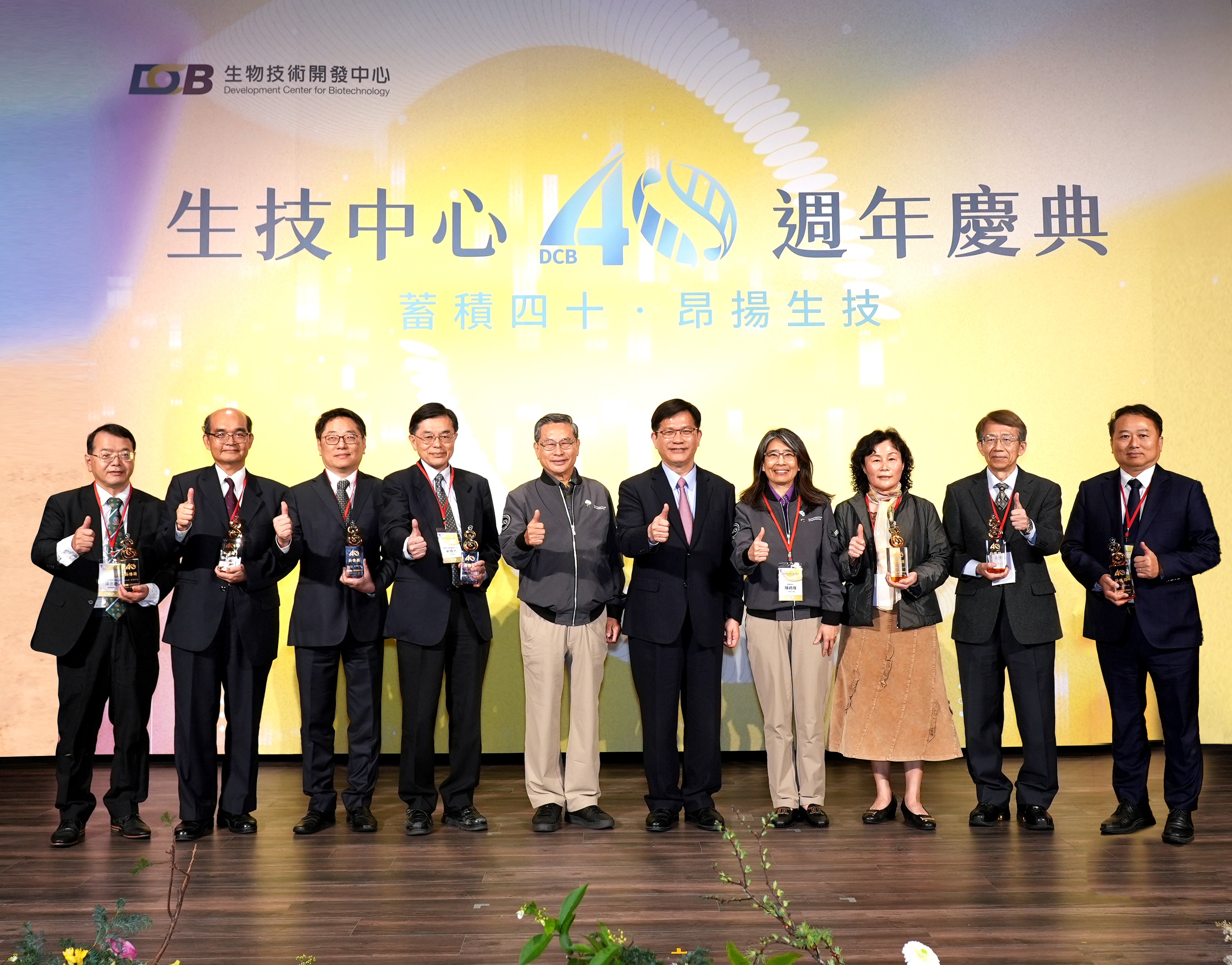 這張圖片顯示了一群人在台上合影，背景有「生技中心 40 週年慶典」的字樣，